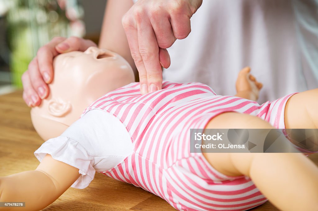 istockphoto-471478278-1024×1024 Woman showing infant CPR on training doll. Performing two finger chest compression.